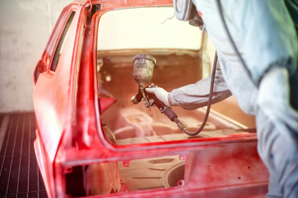 paint engineer working on red car in painting booth